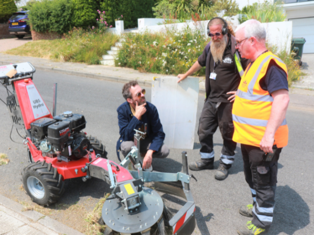 Photograph of three men standing around a weeding machine.