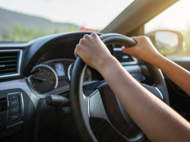 hands on a steering wheel of a car