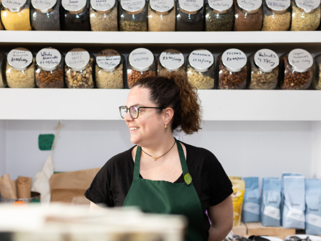 A photo of Harriet of Harriet's of Hove stood in front of a shelf in her refill shop