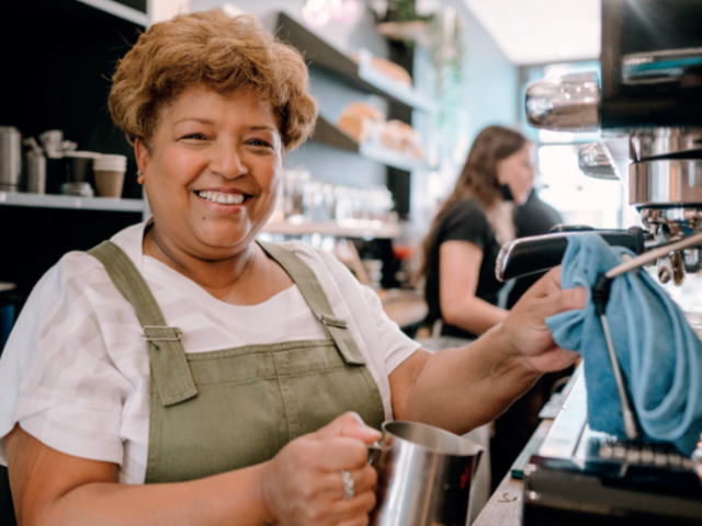 Older woman smiling and making a coffee with a coffee maker