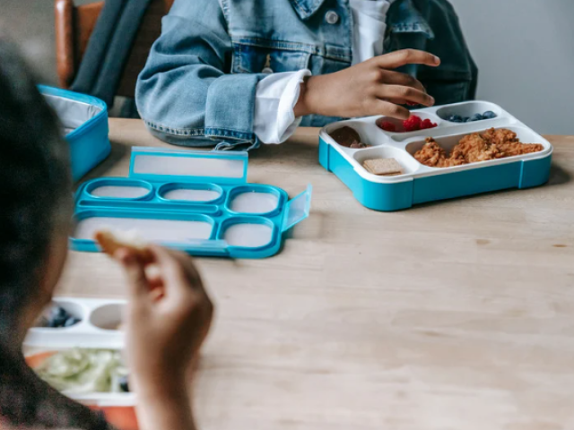 Picture of a child eating a packed lunch at a table.