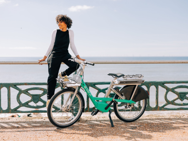 A woman sitting on a railing next to a Beryl BTN Bike