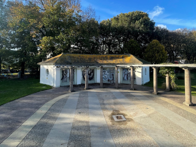 Photograph of a white pavilion building surrounded by trees.