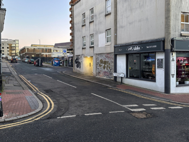 a picture of a road junction with a shop on the corner