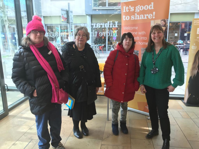 Image of four shared lives carers standing in front of a window smiling.