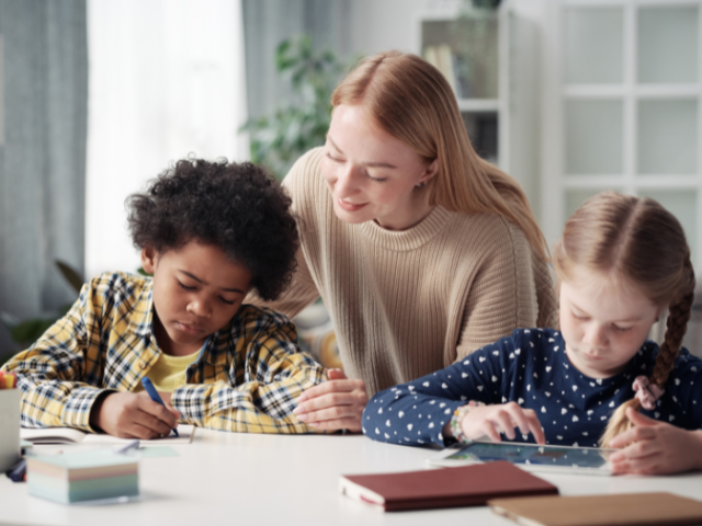 A woman helping two children with their homework