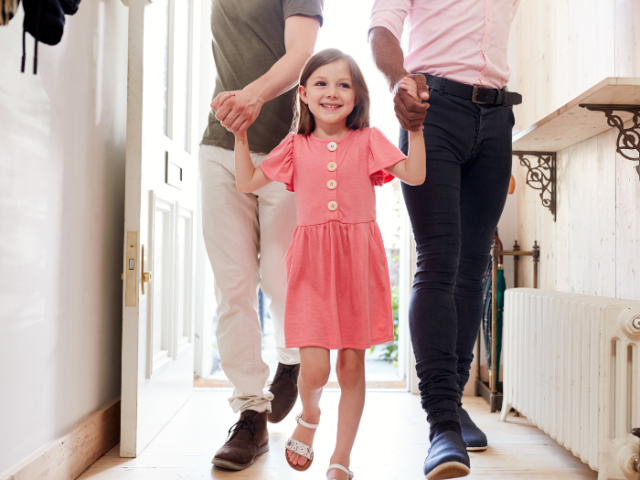 Two people walking into a hallway holding hands with a child