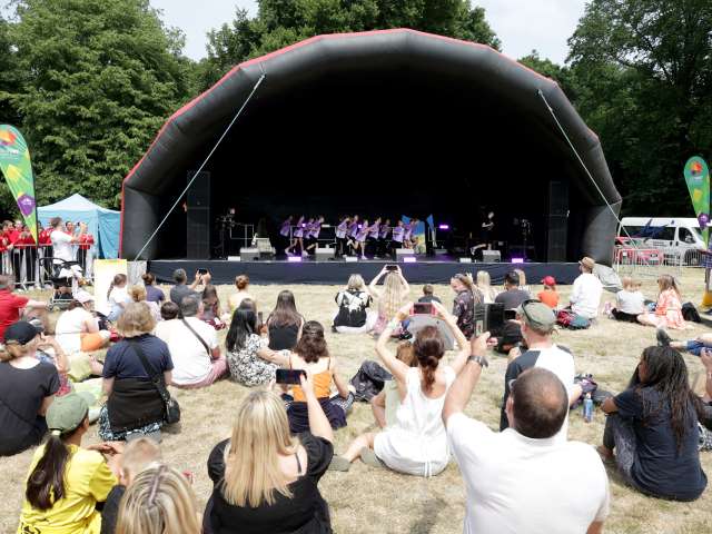 people sat on grass watching dancers on a stage 