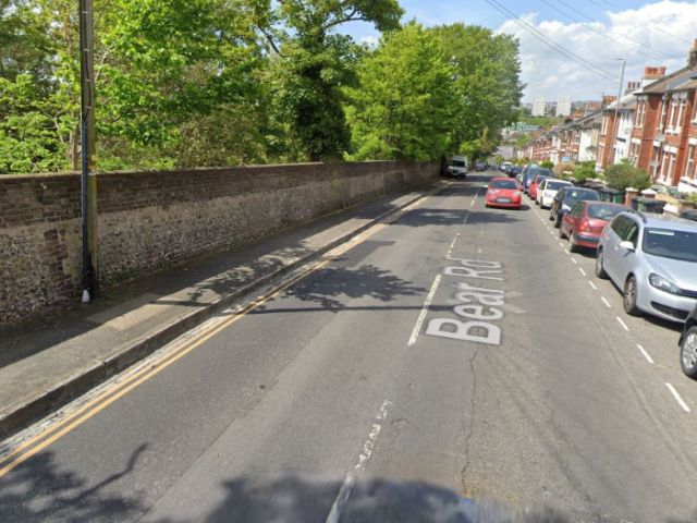 A picture of a road with cars parked along one side