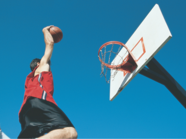 Picture of a basketball player leaping into the air about to score.