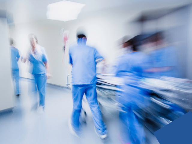 The image shows a busy team of doctors and nurses on a hospital corridor.