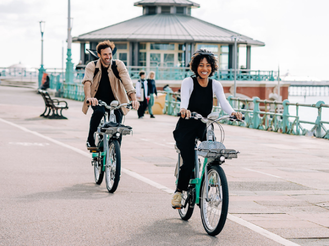 Two people riding bikes along Brighton seafront