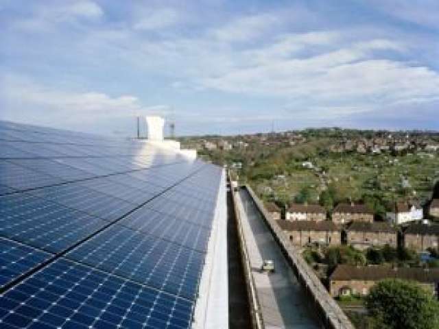 Solar panel array on a Brighton rooftop, with a housing estate and fields in the background