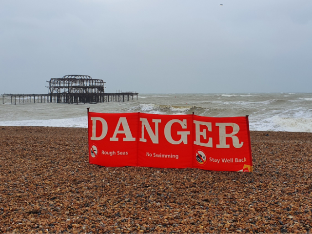 Picture of Brighton beach and a large red Danger sign