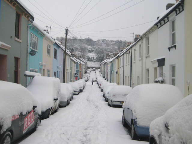 The photo shows a street in Brighton with colourful terraced houses covered in snow.