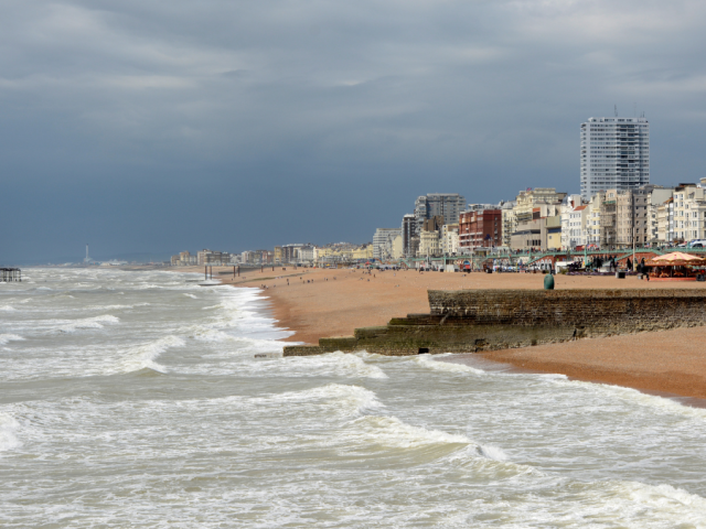 View of Brighton seafront with the sea on the left, West Pier in the distance and buildings on the right