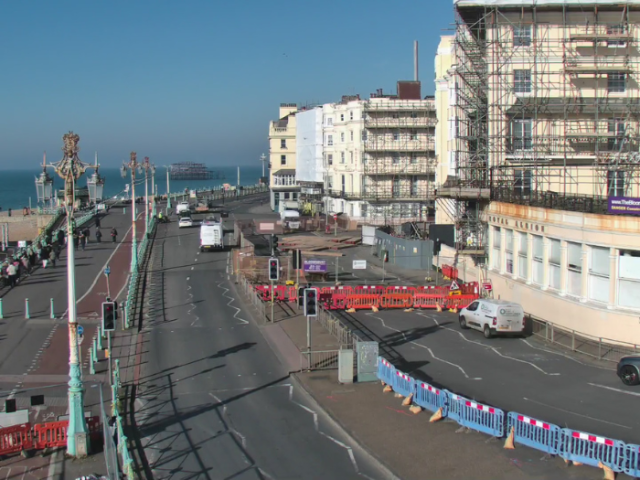 A picture of a road with barriers on one side and a hotel surrounded by scaffolding