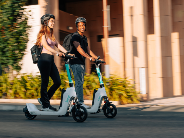 two people riding electric scooters
