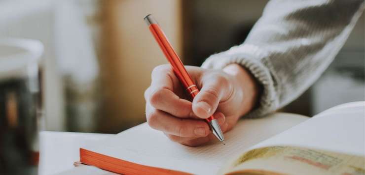 A person using a pen to write in a book