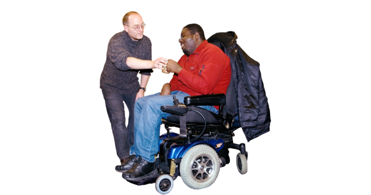 A person handing a person in a wheelchair a drink. 