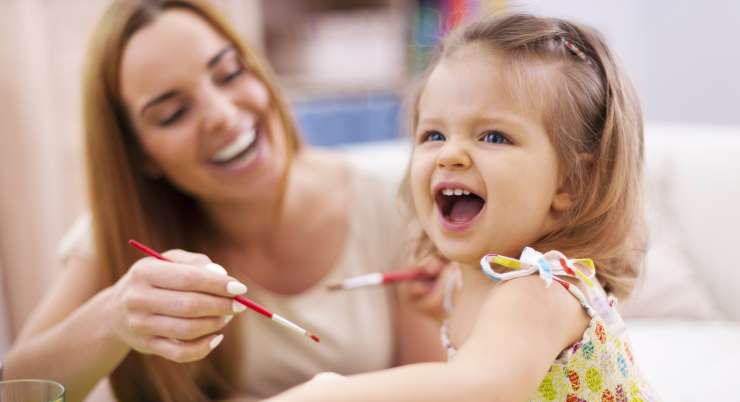 Adult smiling and painting with toddler