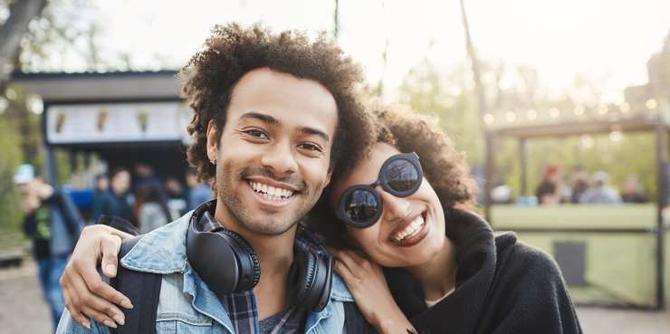 Adult and teenager smiling. The adult is hugging the teenagers shoulders