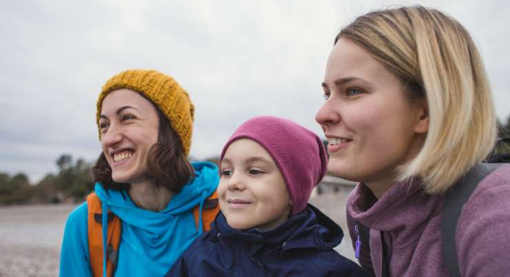 2 adults and a child outdoors in winter clothing, smiling and looking into the distance