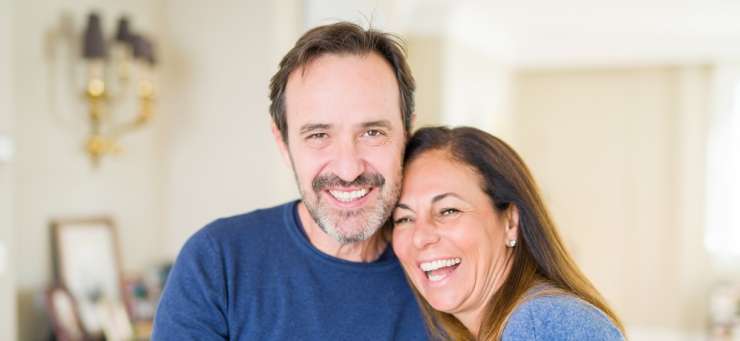 2 adults smiling to the camera in a living room