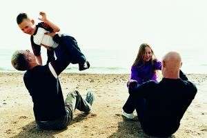 Photograph of two children and two adults happily playing on the beach