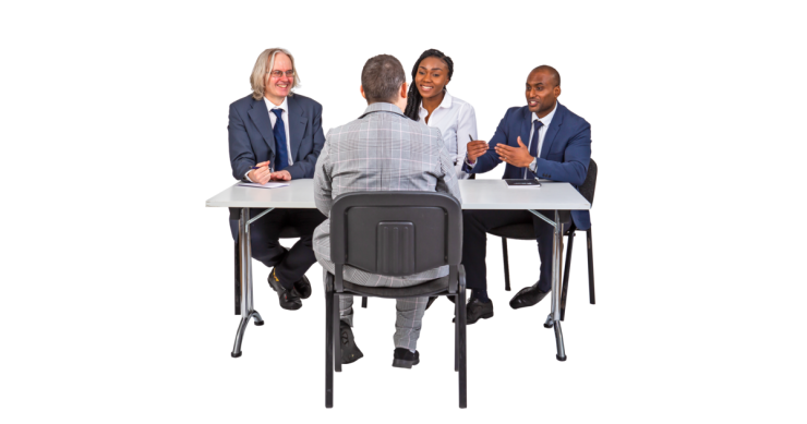 An interviewee sitting at a table in front of 3 interviewers.