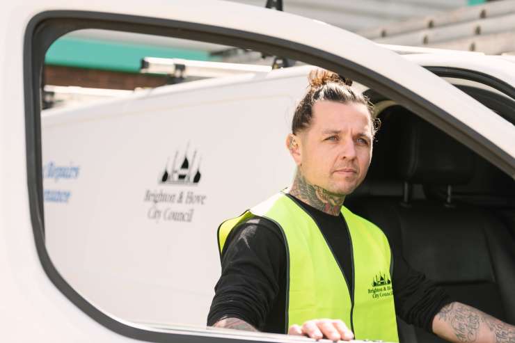 A Brighton & Hove City Council worker in about to get into a white Brighton & Hove City Council van. They are wearing a yellow high-vis vest.